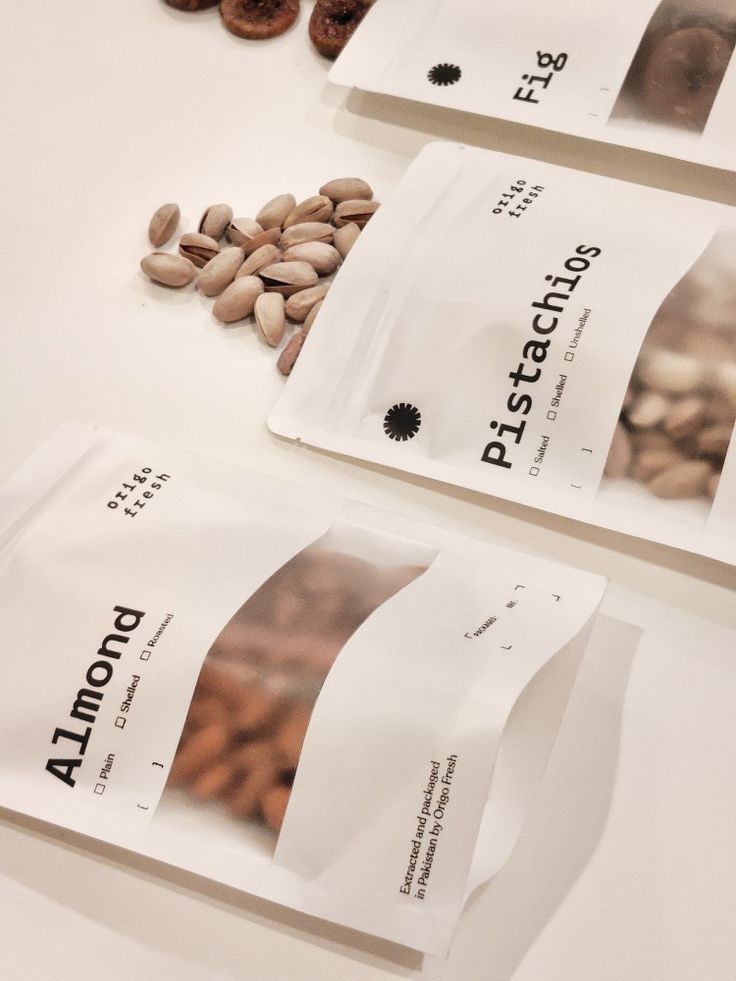 three packets of almonds and pistachio nuts on a white counter top with the labels printed out