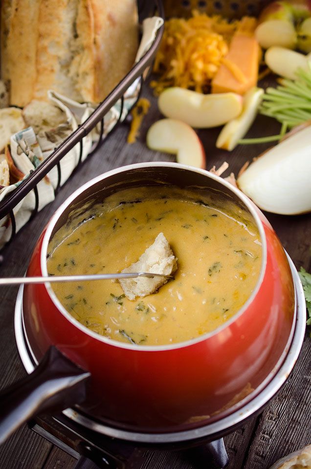 a red pot filled with soup sitting on top of a wooden table next to bread