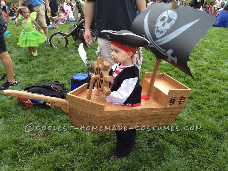 a little boy dressed up as a pirate in a boat with a skull and crossbones on it