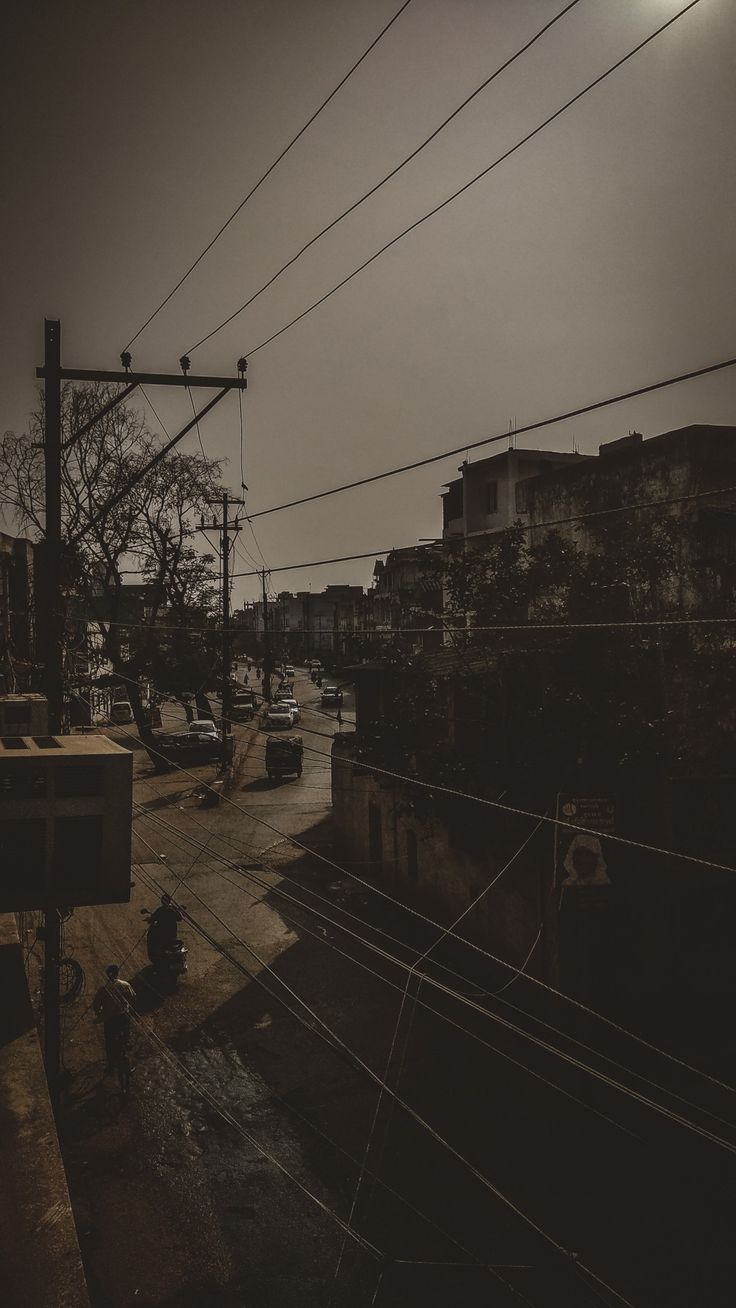 an empty street with power lines above it and cars parked on the side of the road