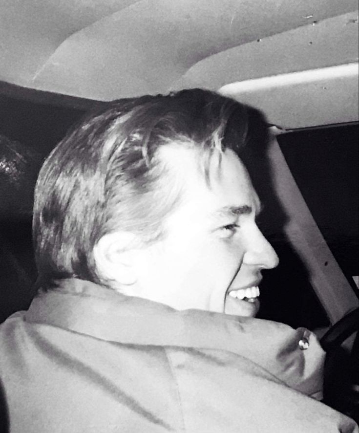 black and white photograph of man in car laughing