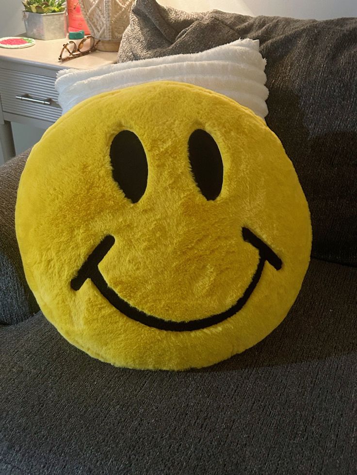 a yellow smiley face pillow sitting on top of a couch