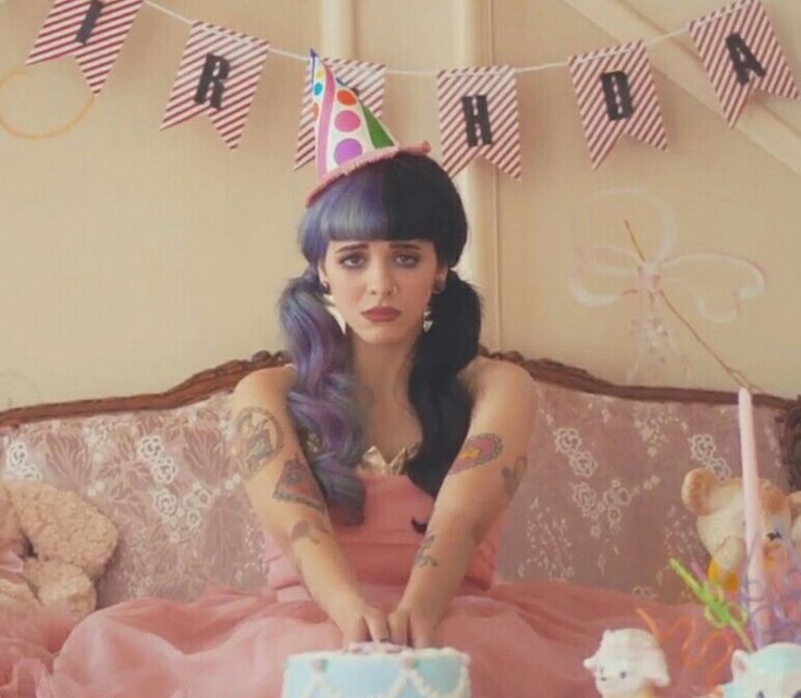 a woman sitting on top of a pink couch next to a cake and teddy bears