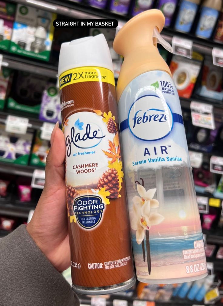 someone is holding two spray bottles in front of a store shelf with other items on it