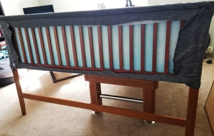 a baby crib with blue and red stripes on the top, sitting in a living room