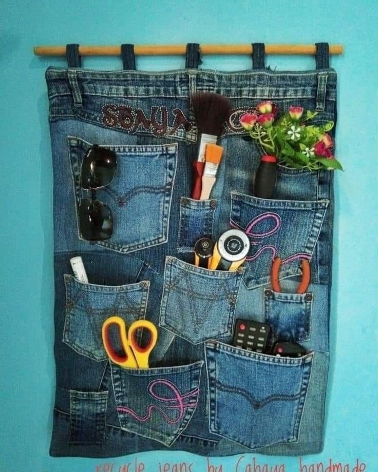 an old pair of jeans hanging on a wall with some scissors and other items in it