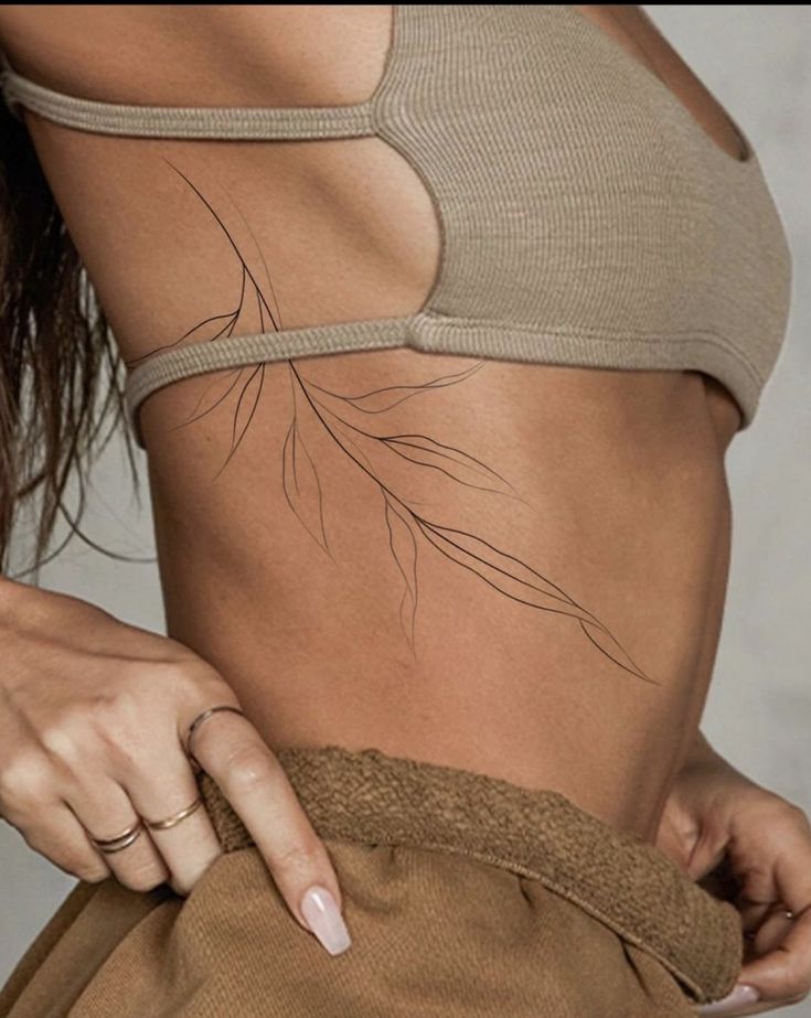 a woman is showing off her stomach with tattoos on the side and behind her waist