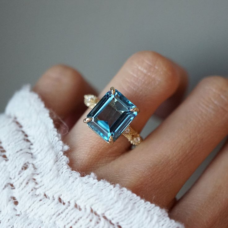 Delight in the romantic summer reverie of this beautiful big London Blue Topaz ring - featuring intricate lace-like details along the band with natural diamonds. Perfect for dreamers and romantics alike. Handcrafted in your choice of 14K or 18K gold. 14K or 18K solid gold 10*8mm emerald-cut natural London Blue Topaz Natural round white diamonds 1.5mm band thickness ** This item is specially made for you. Please allow 2-3 week lead time. Shipping:Domestic: Free standard shipping within the U.S.In Weddings Rings, Color Stones Jewelry, Ring Cuts, Fall Rings, Romantic Summer, Emerald Cut Rings, Beach Bridal, Stones Jewelry, London Blue Topaz Ring