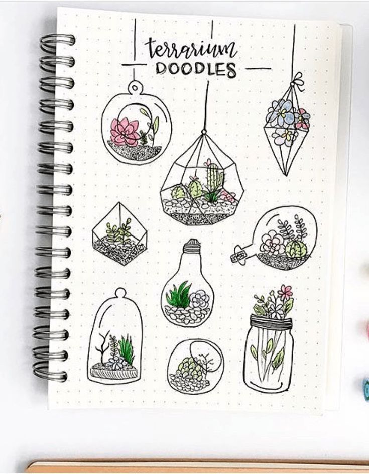 an open notebook with drawings on it and flowers in vases hanging from the top