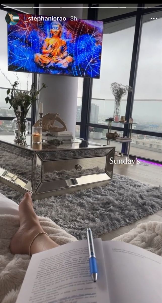 a person laying on a bed reading a book in front of a large screen tv