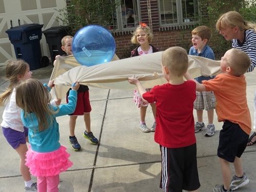 a group of children playing with bubbles in front of a house