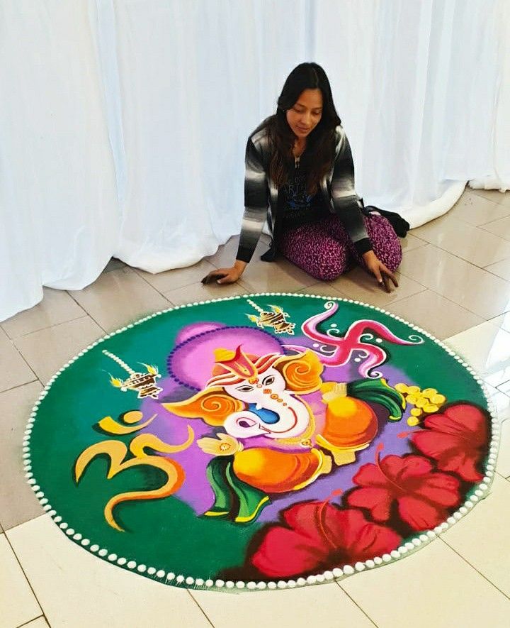 a woman kneeling down on the floor in front of a colorfully painted round rug