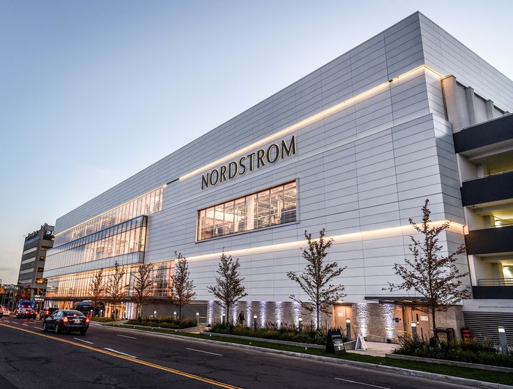 a large white building with lights on it's side and cars parked in front