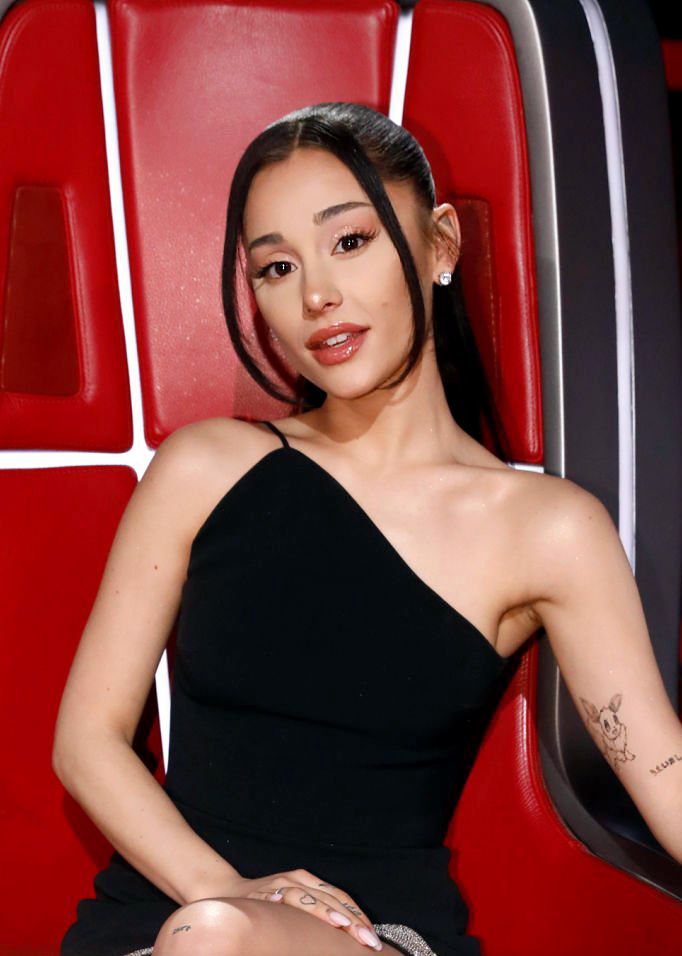 a woman in a black dress sitting on a red chair and posing for the camera