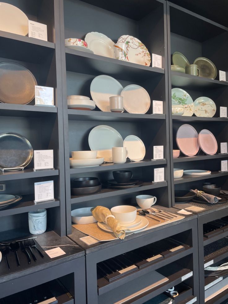 the shelves are full of dishes and plates for sale at the store or showroom