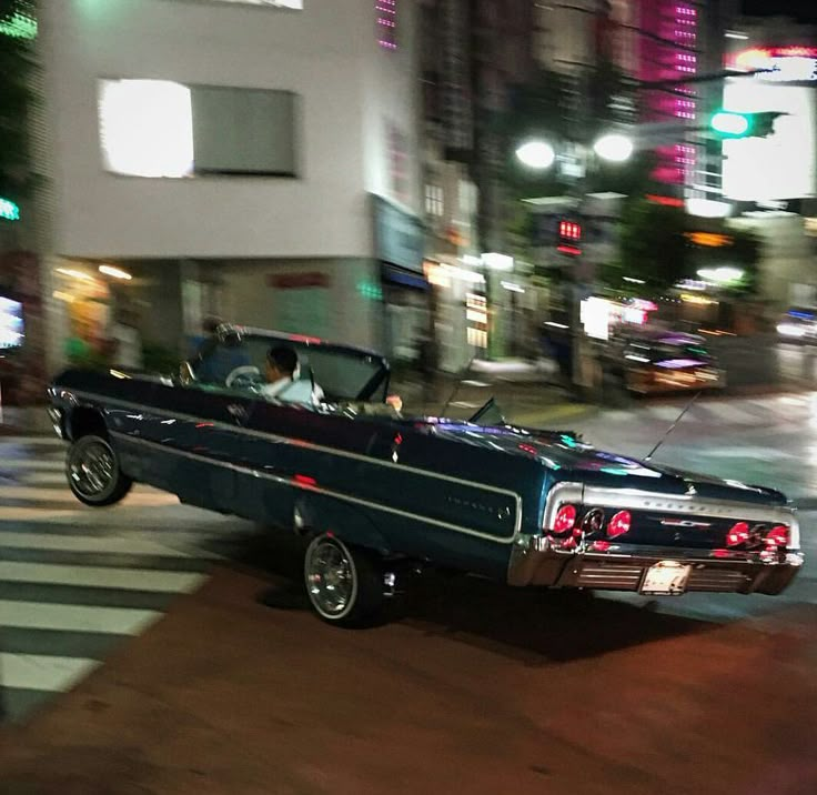 an old car driving down the street at night