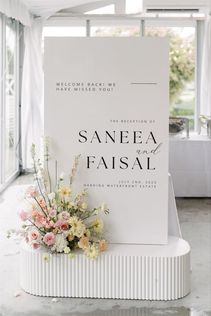 a white sign with flowers on it in front of a glass wall that reads sanee and fasal