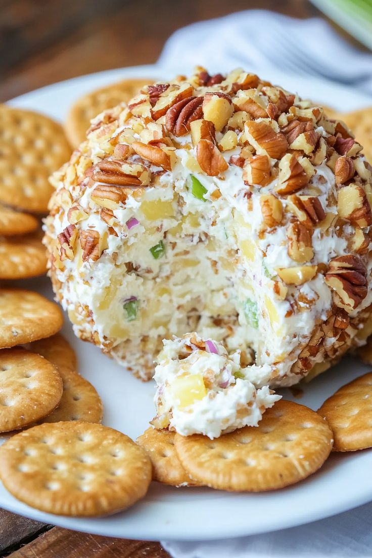 a cheese ball covered in nuts on a plate with crackers