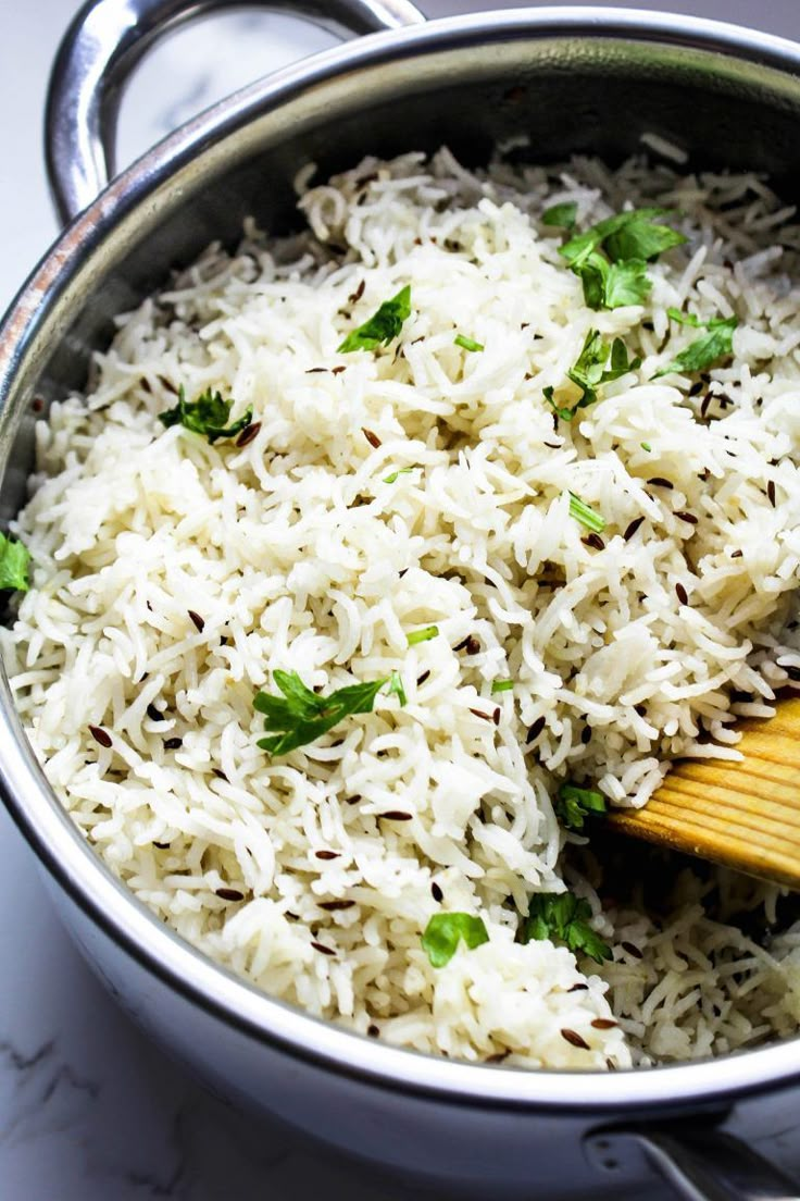 white rice and parsley in a pot with a wooden spatula on the side