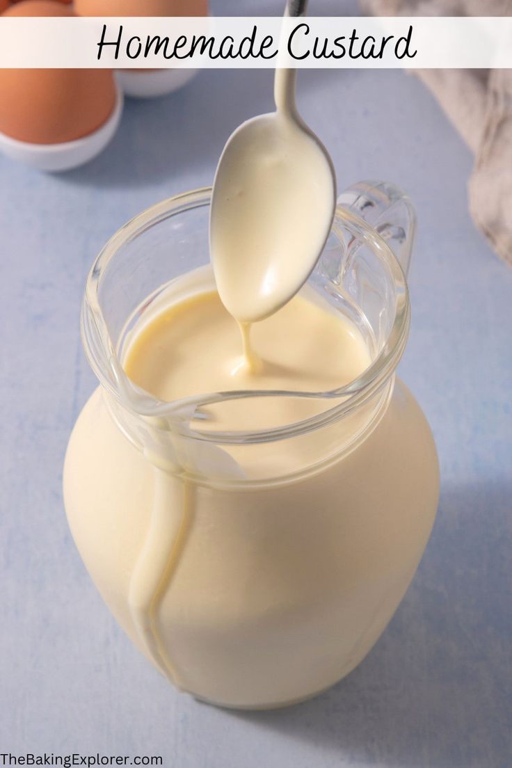 a glass jar filled with homemade custard on top of a blue table next to eggs