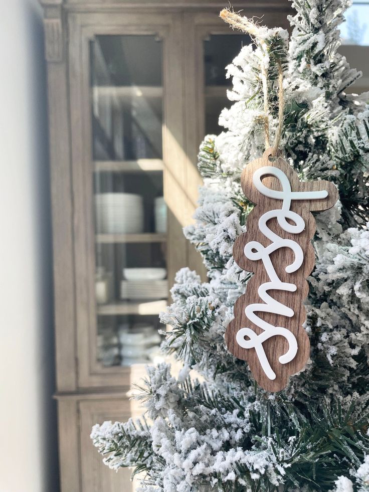 a wooden ornament hanging from the top of a christmas tree with snow on it