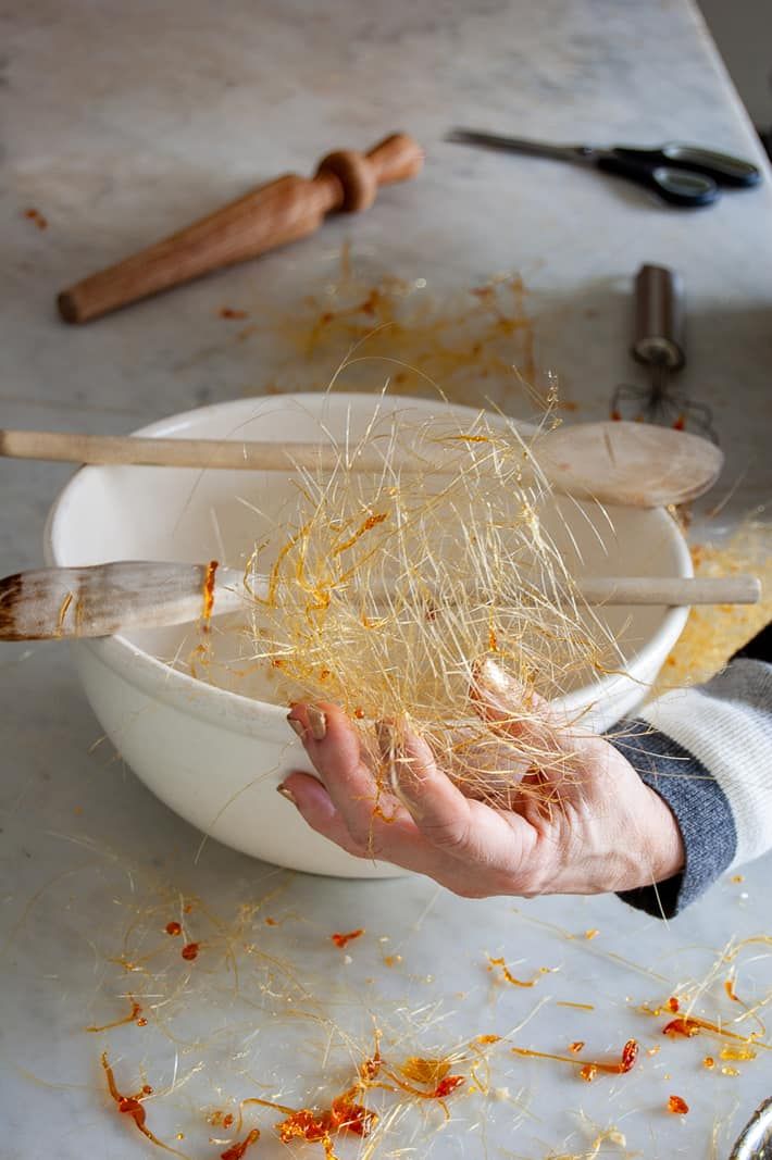 a person holding chopsticks over a white bowl filled with shredded cheese and other ingredients