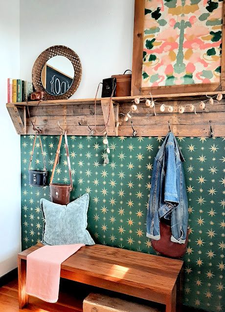 a wooden bench sitting in front of a wall mounted coat rack with hooks on it