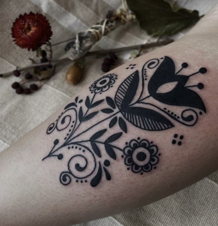 a black and white tattoo on the arm of a woman's leg with flowers