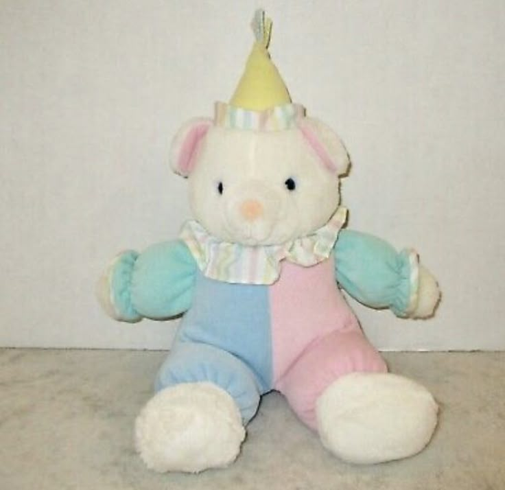 a teddy bear with a party hat on it's head and leg sitting in front of a wall