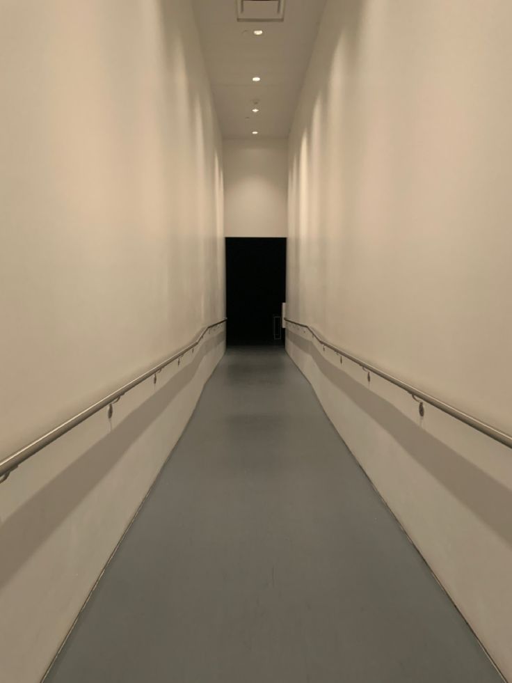 an empty hallway with white walls and gray flooring