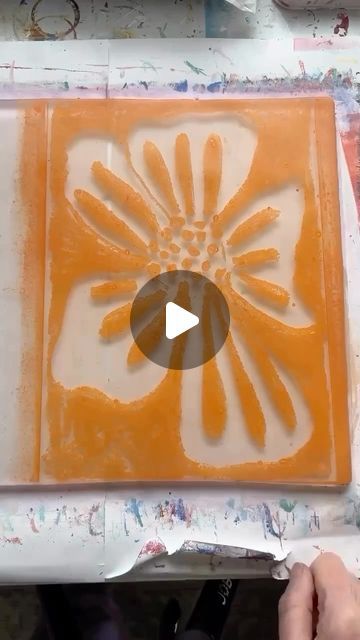 a person is painting on a tile with orange and white colors in the process of being made