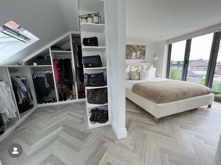 a bedroom with a bed, closets and clothes on shelves next to the window