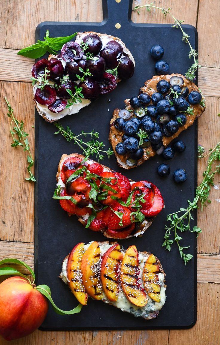 a black cutting board topped with fruit and bread