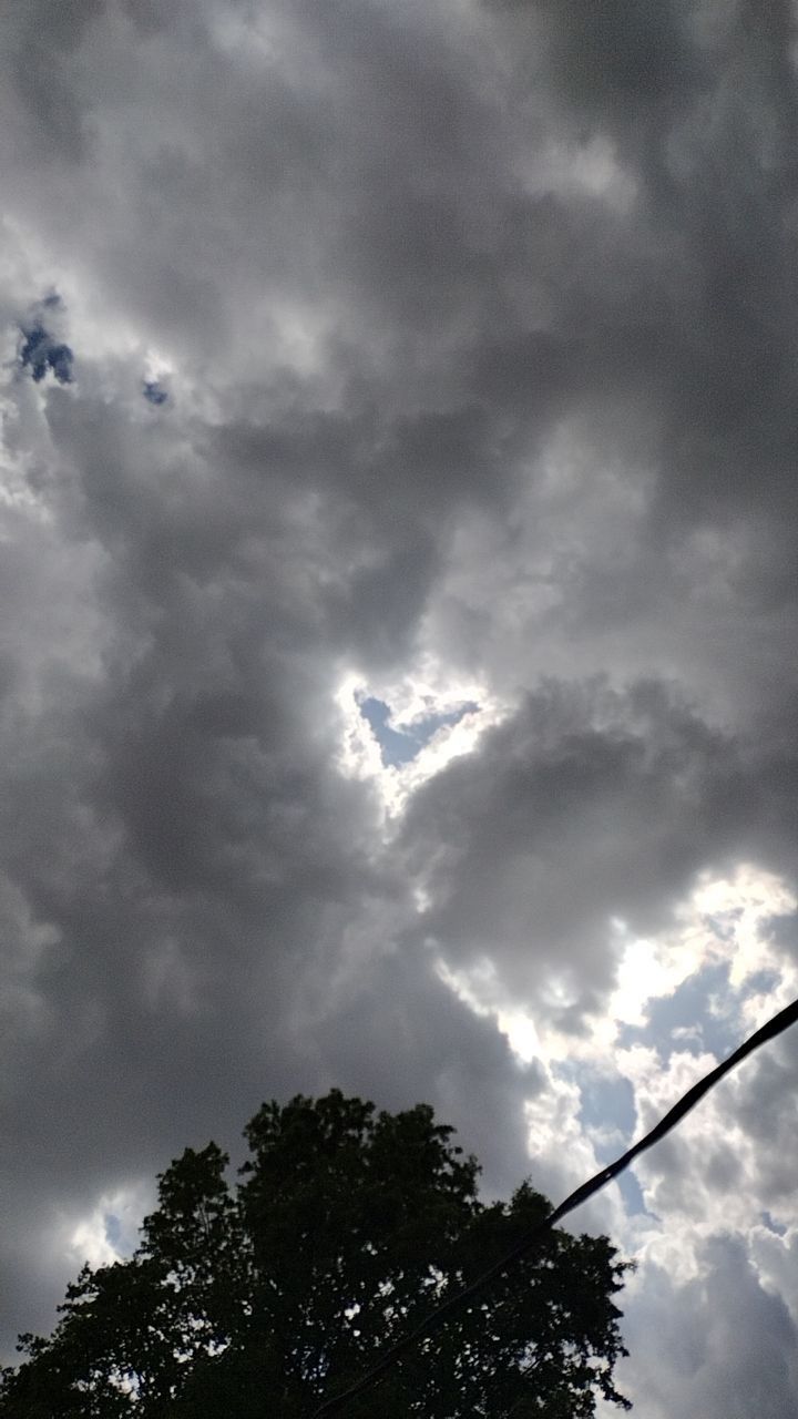 the sky is full of clouds and some power lines in front of trees on a cloudy day