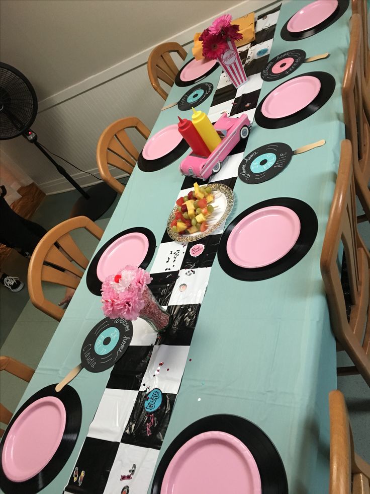 the table is set up with pink and black plates, napkins, and candy