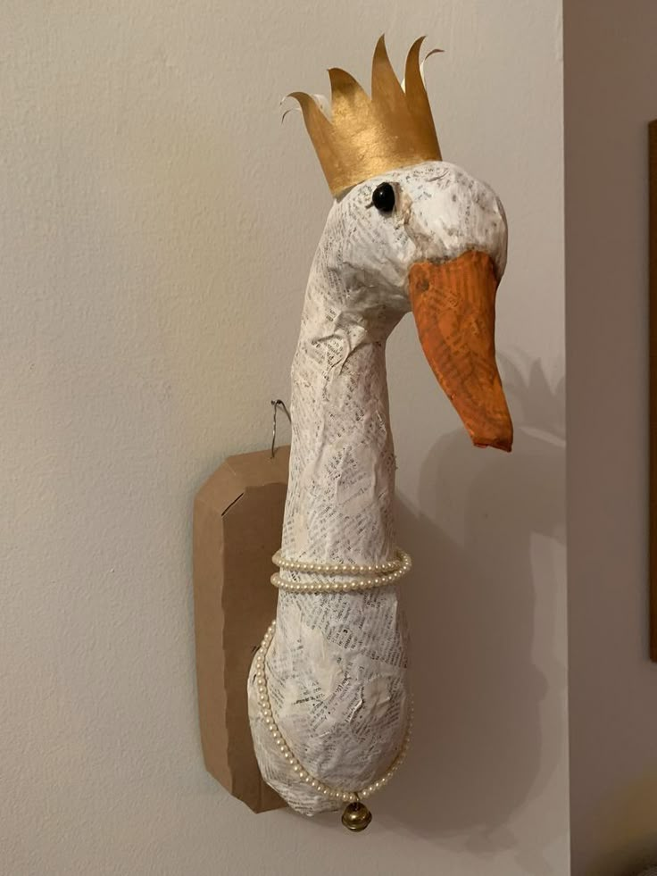 a white bird with a golden crown on it's head hanging from a wall