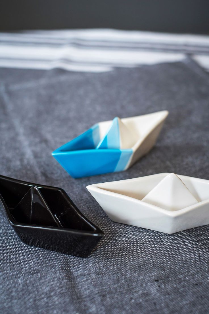 three small boats sitting on top of a gray surface next to each other, one blue and one white