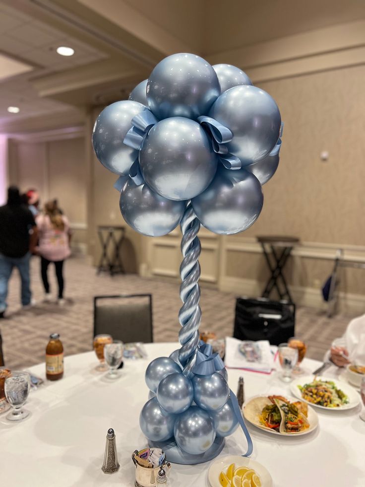 a table topped with balloons and plates filled with food on top of a white table cloth