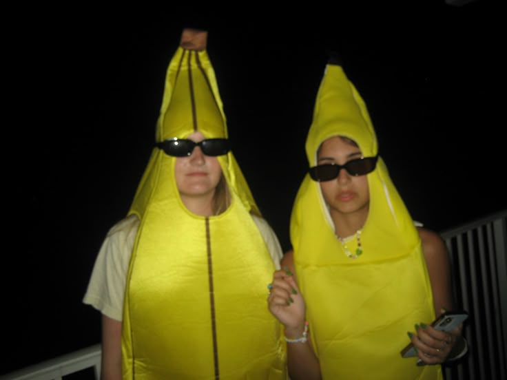 two women dressed in banana costumes standing next to each other with sunglasses on their heads