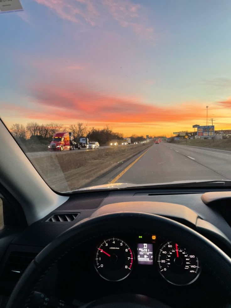 the dashboard of a car on a highway at sunset