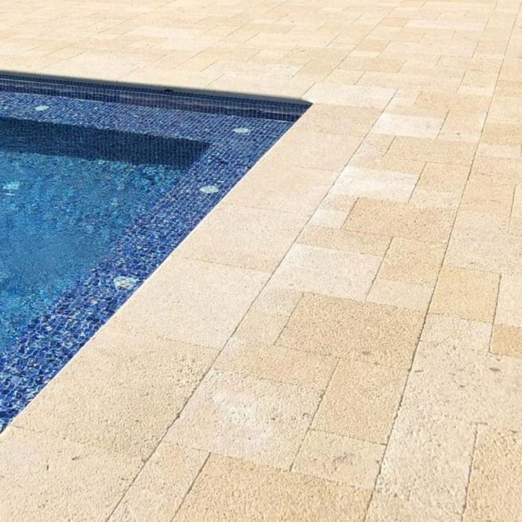 an empty swimming pool surrounded by stone pavers