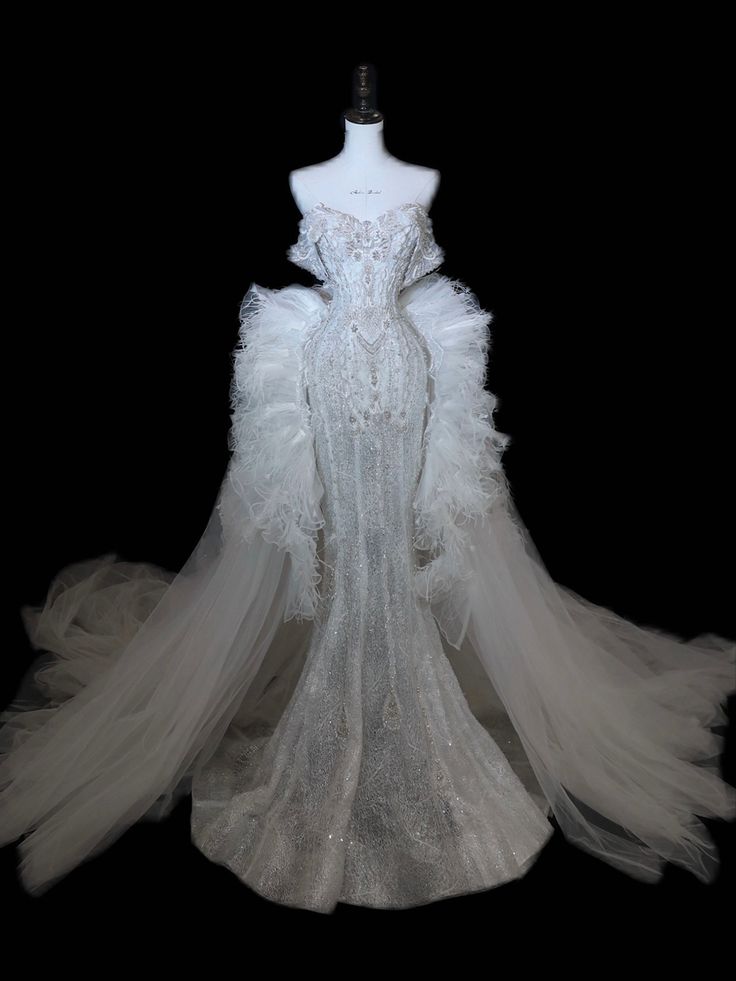 a white wedding dress on display in front of a black background