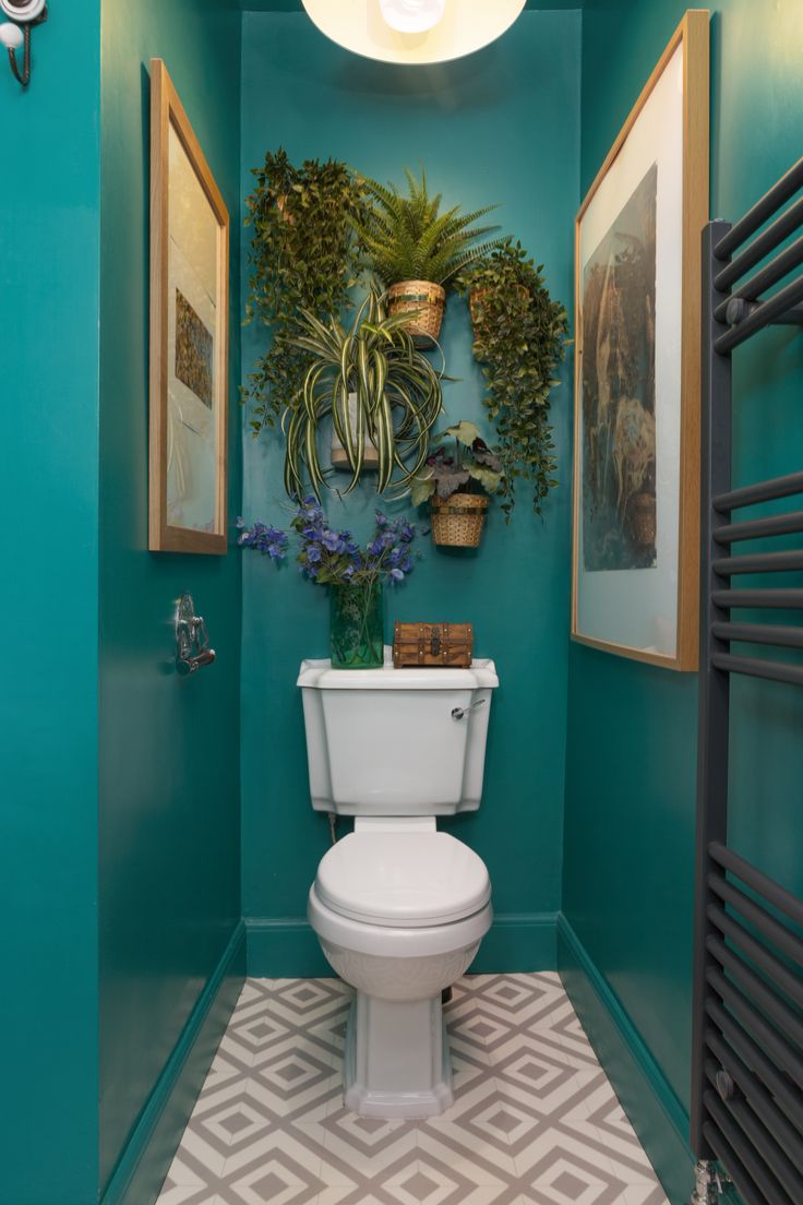 a white toilet sitting in a bathroom next to a green wall and potted plant