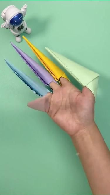 a hand holding an origami airplane with four different colors