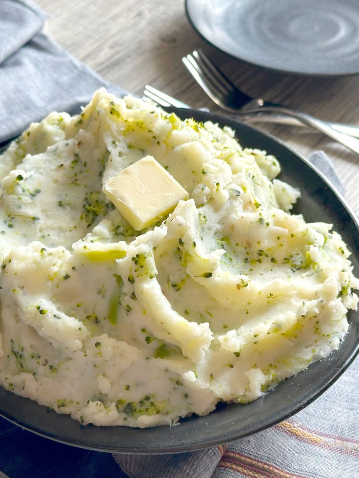 mashed potatoes with butter and seasoning in a black bowl on a wooden table