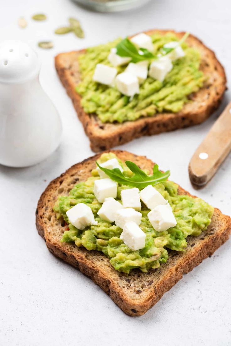 two pieces of bread topped with guacamole and feta