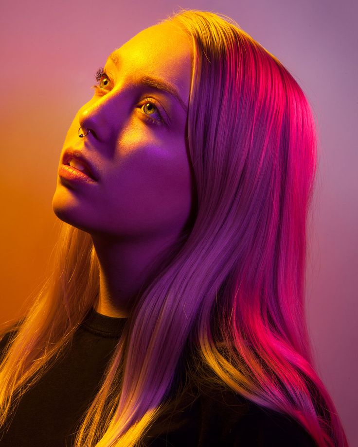 a woman with bright pink hair is looking off into the distance