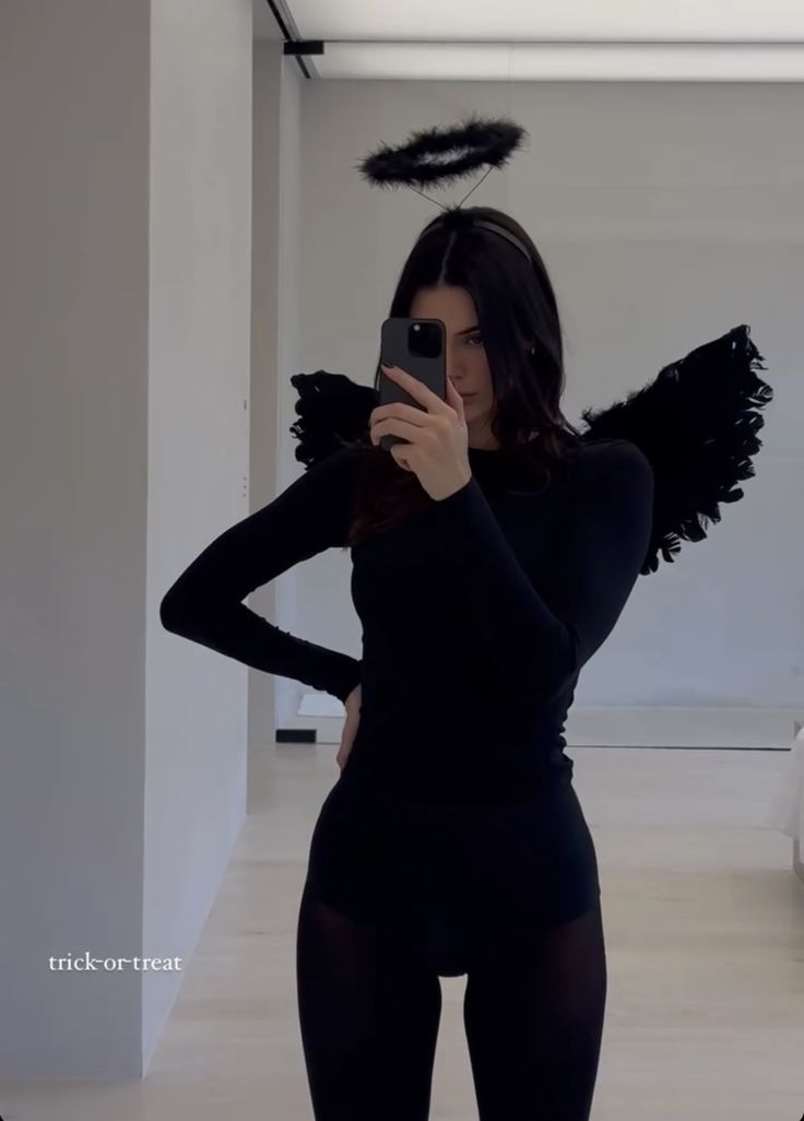 a woman is taking a selfie with her cell phone while wearing an angel costume