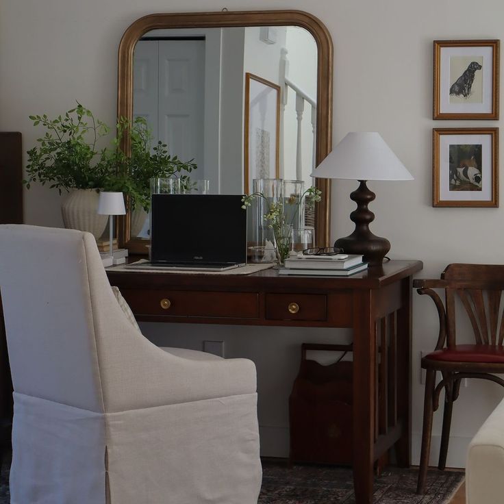 a desk with a chair, lamp and pictures on the wall