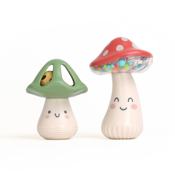 two ceramic mushrooms with faces on them sitting next to each other in front of a white background